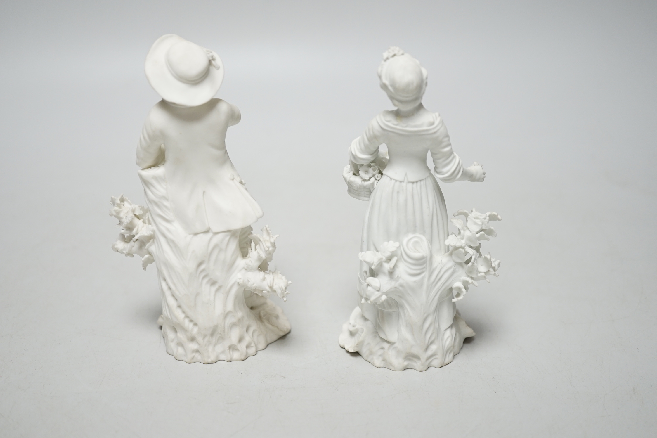 A pair of 18th century Derby biscuit figures of a man and woman, he with a bunch of grapes and she with a basket of flowers possibly representing Spring and Autumn, pattern number 125